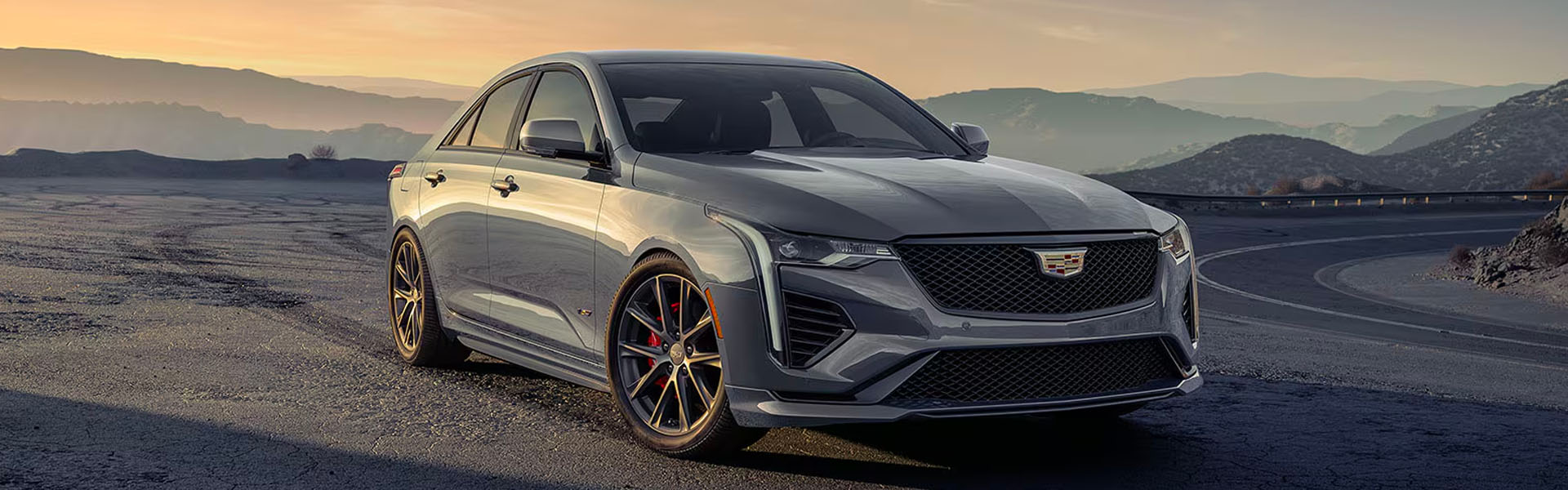 2025 Cadillac CT4-V gray performance sedan parked on a winding mountain road at sunset