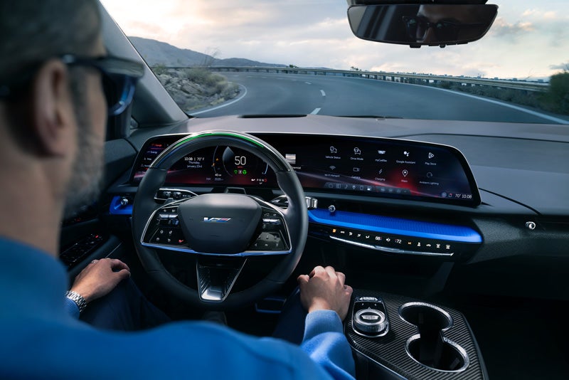 Front View of the 2026 OPTIQ-V Driving Through the Dusk Utilizing its Headlights | AutoNation Cadillac West Palm Beach in West Palm Beach FL