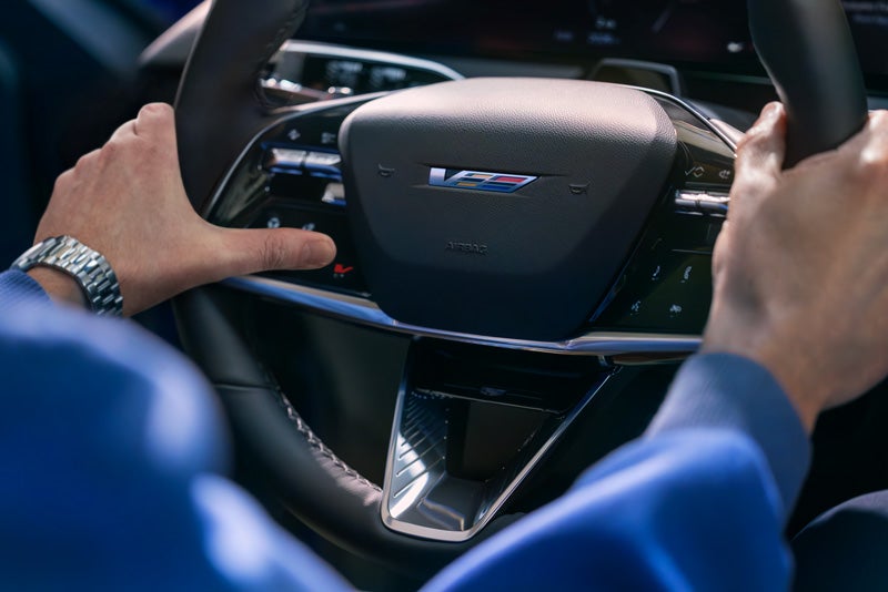 Close-up of a Man About to Press the V-Button on the 2026 OPTIQ-V Steering Wheel | AutoNation Cadillac West Palm Beach in West Palm Beach FL