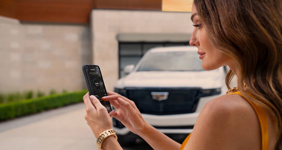 lady checking her mobile with a Cadillac vehicle background | AutoNation Cadillac West Palm Beach in West Palm Beach FL