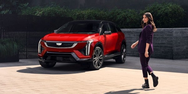 A 2027 Cadillac OPTIQ SUV parked in front of a modern building, showcasing its sleek design and elegant features.