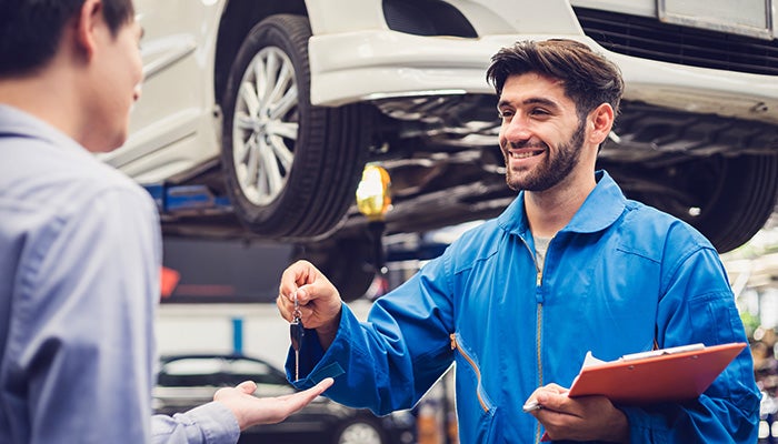 Service expert giving car key to its owner